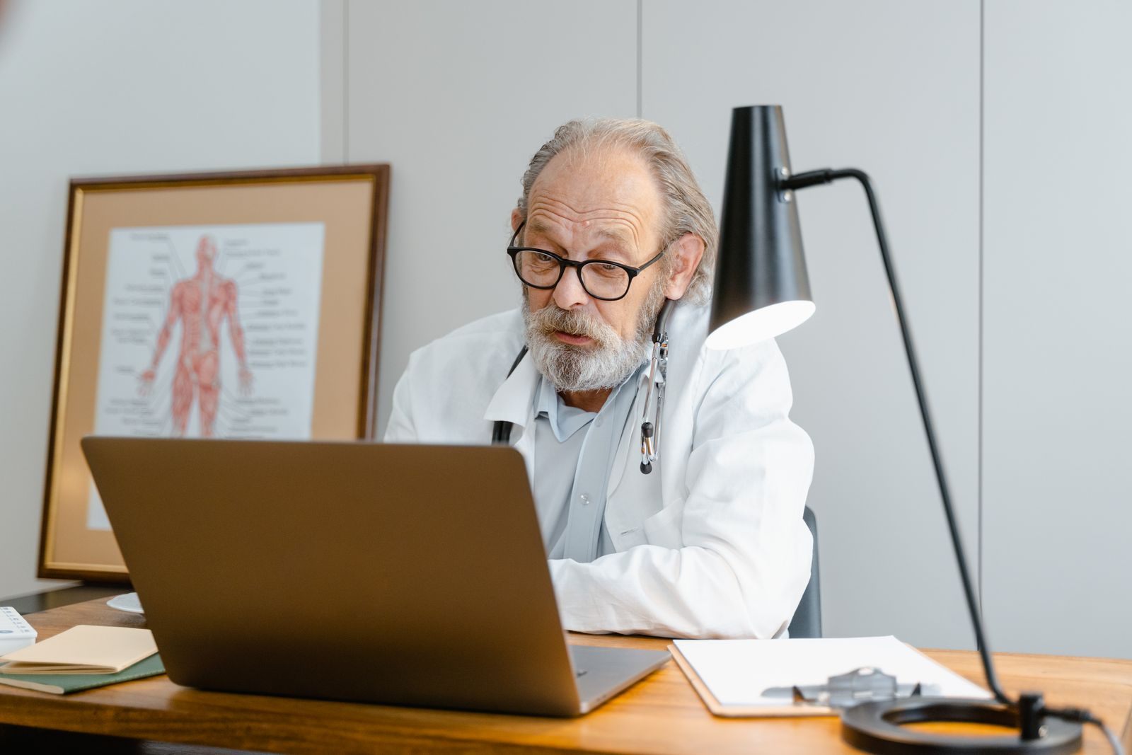 Senior physician working at a laptop in his office, preparing for CME cruises