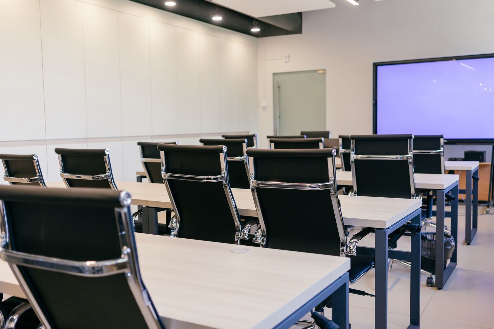 Empty seminar room with desks, chairs and a presentation screen