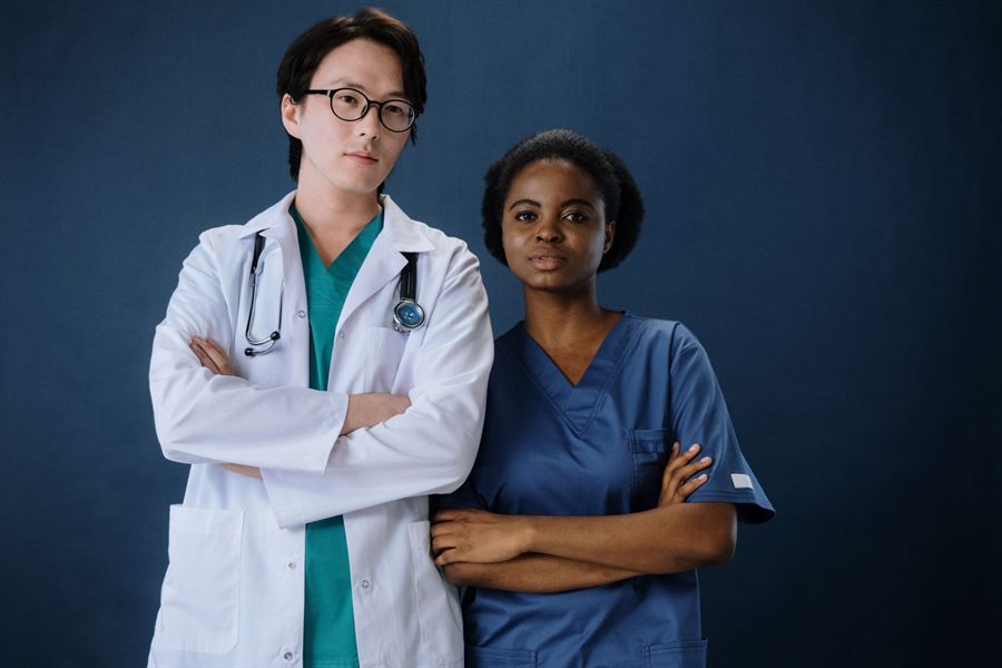 Physician and nurse standing side by side with arms folded