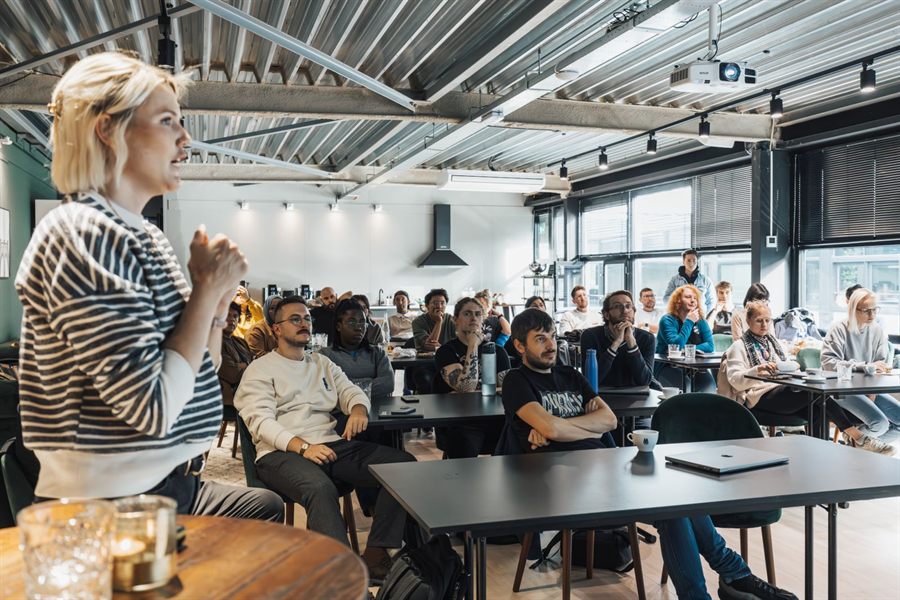 Speaker engaging a seated audience in a modern workshop space